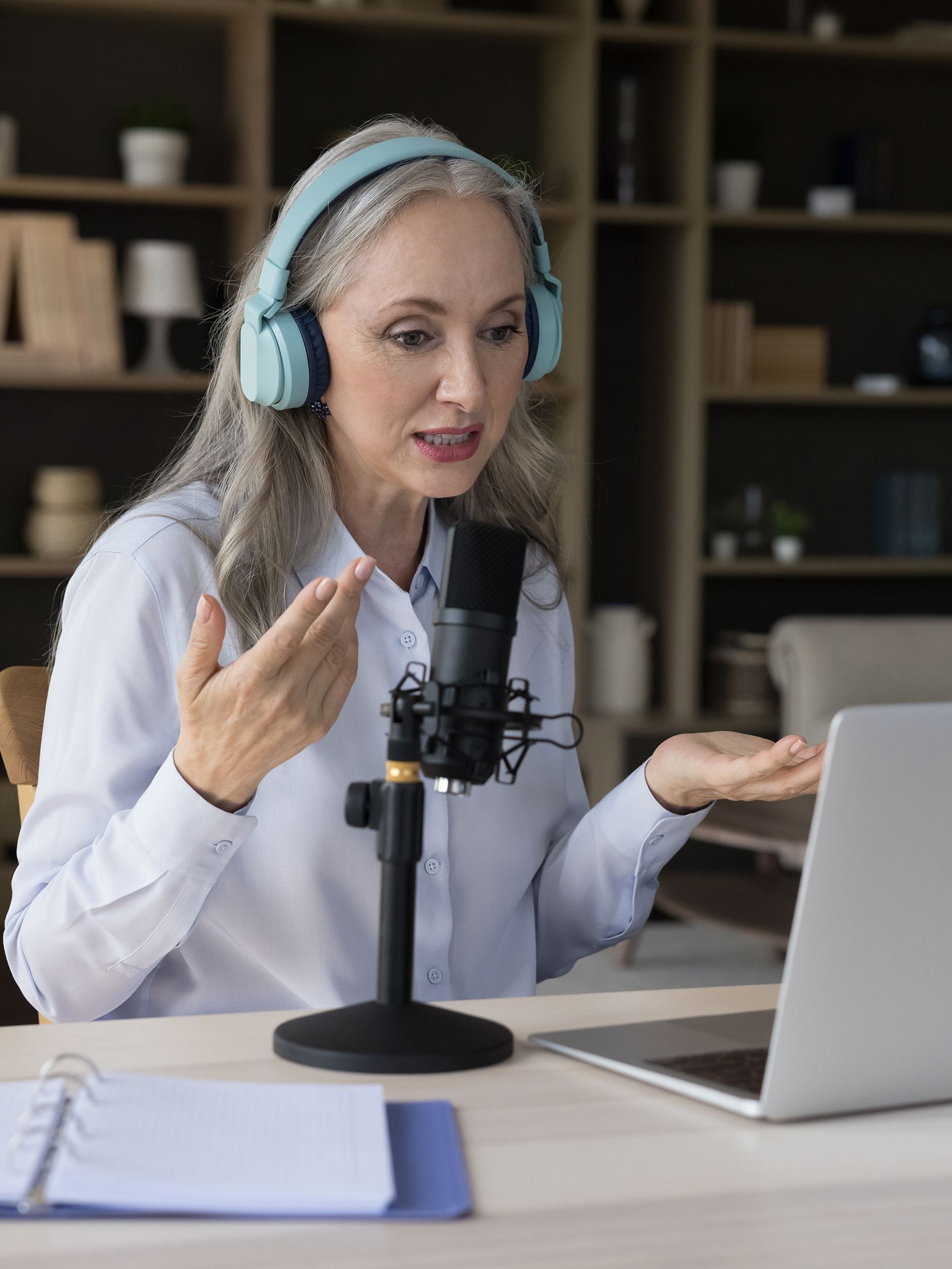 Woman using headphones and a laptop microphone to communicate with someone at another location.