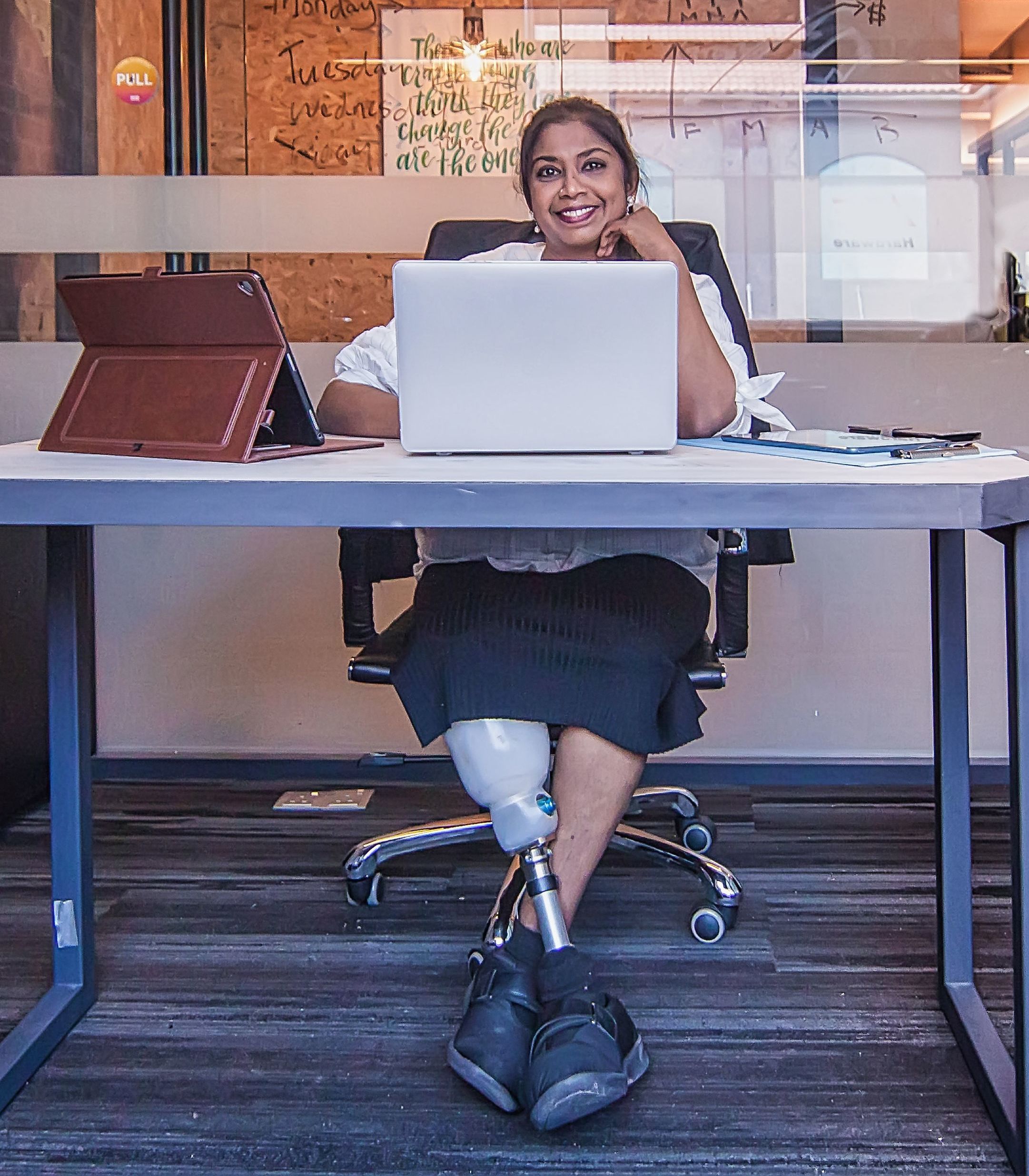 Woman with prosthetic leg sitting at her office space.