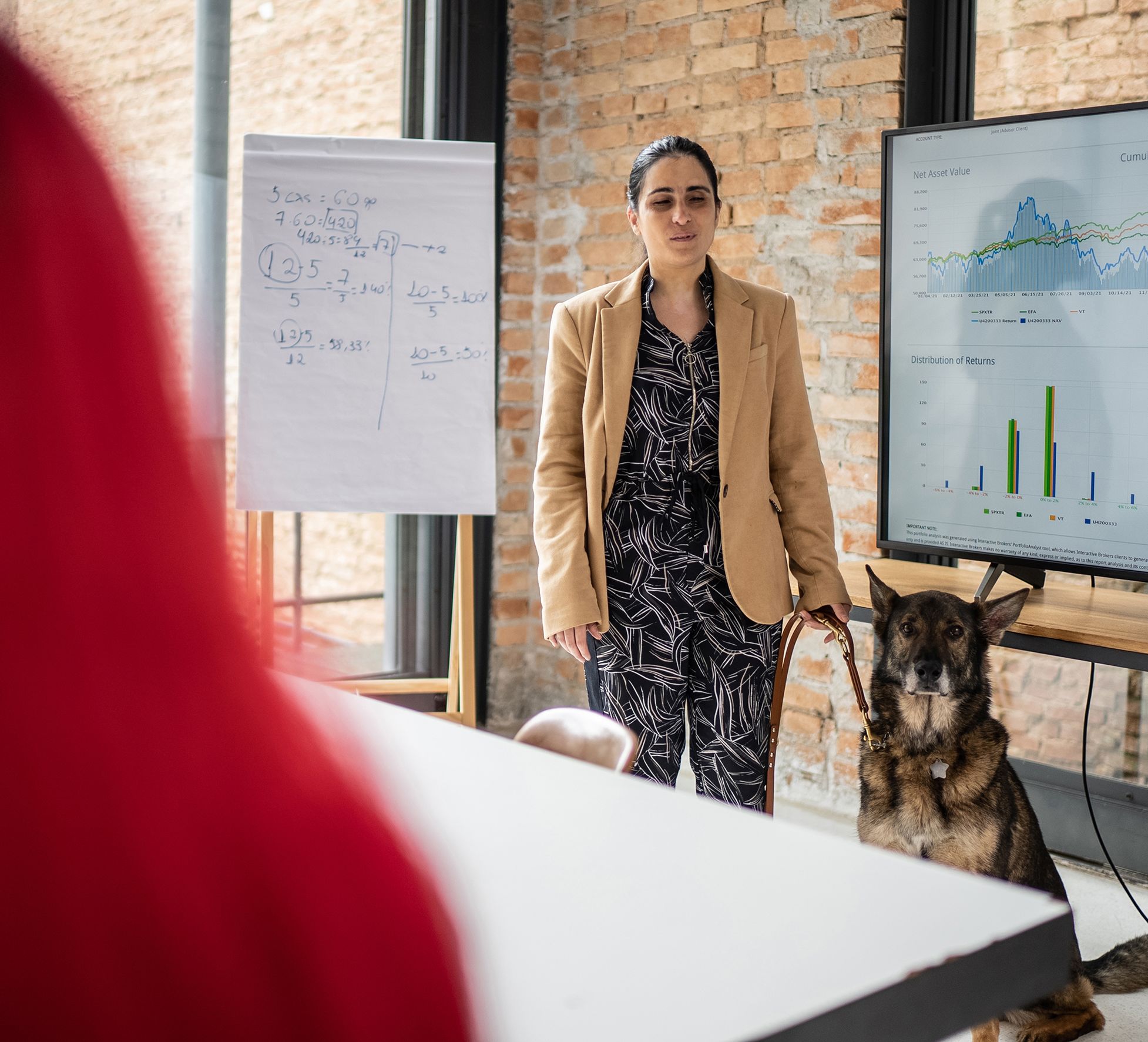 Woman with a guide dog doing a presentation in front of a display.