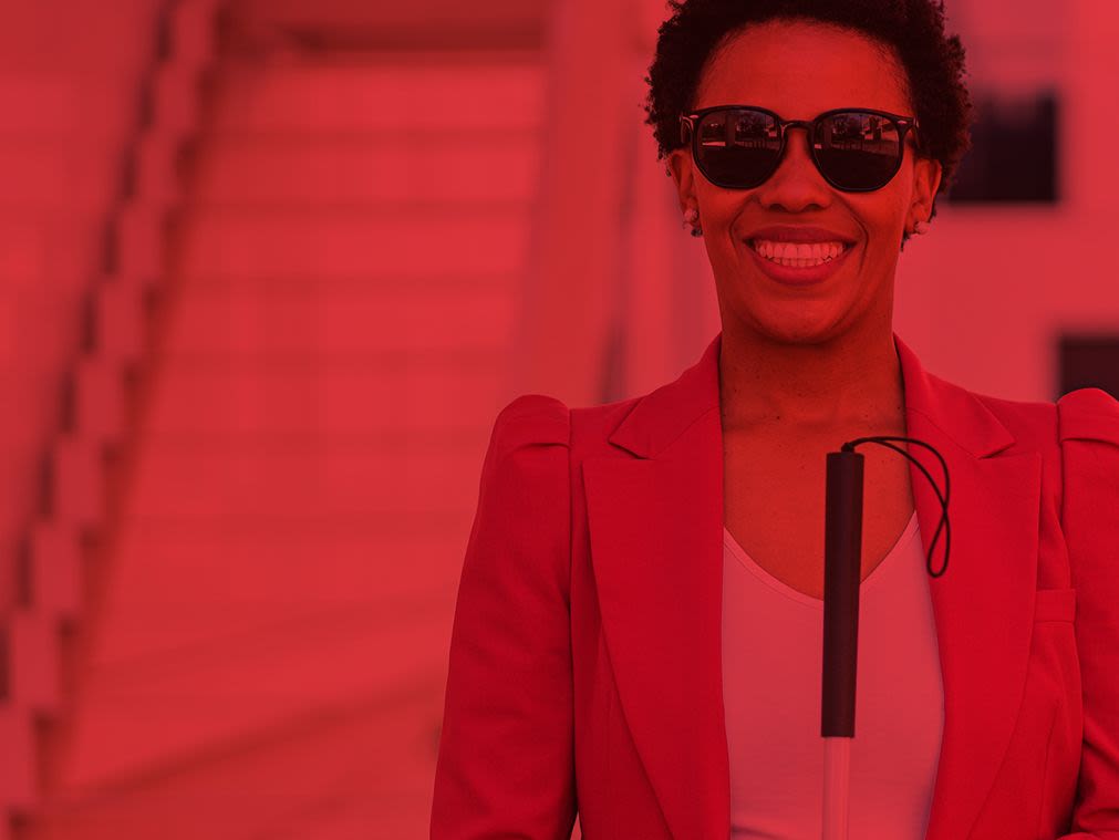 Woman with a white cane smiling.