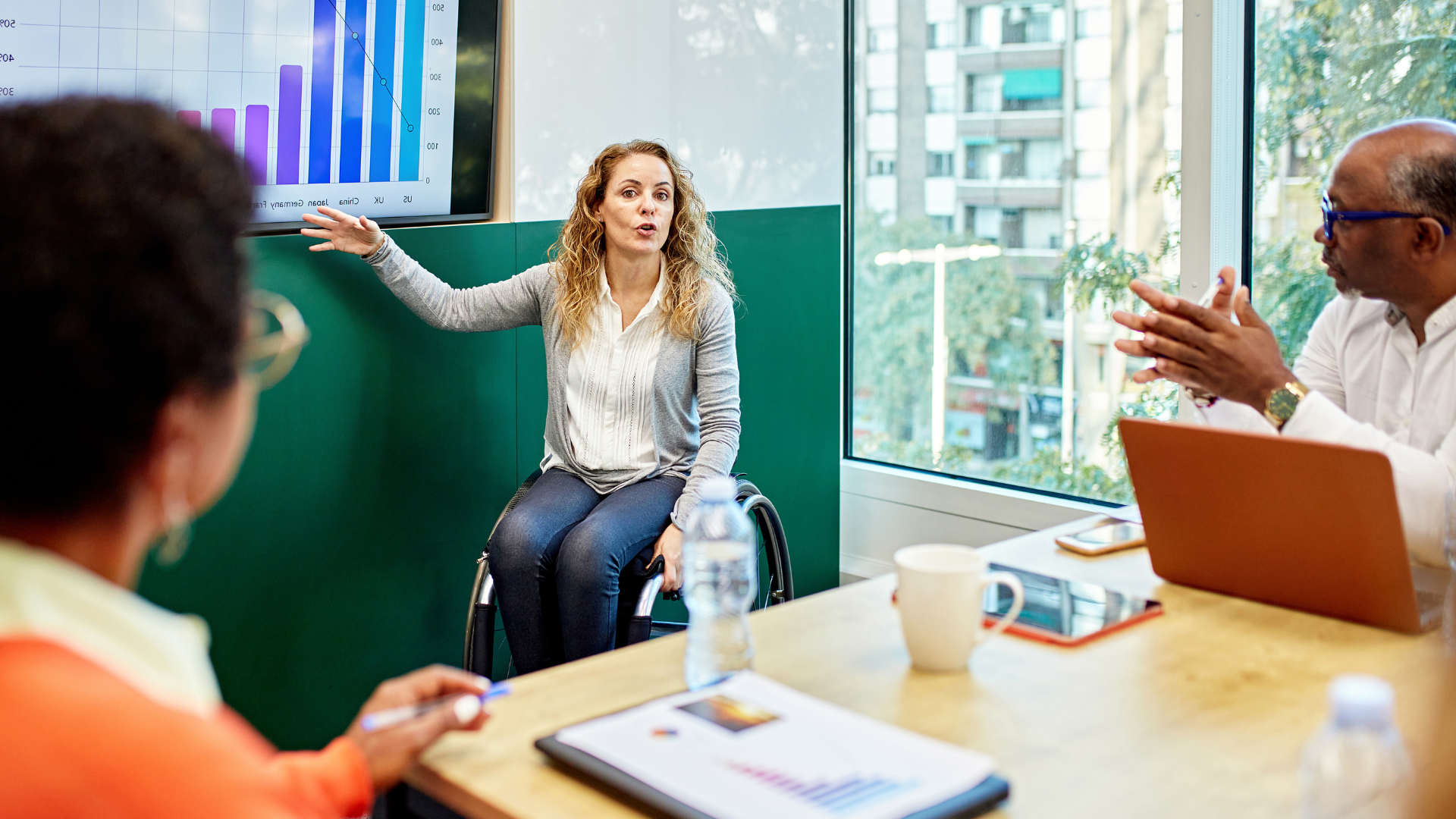 Woman in wheelchair presenting to others in a conference room.