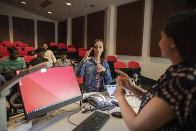 Person using sign language in a university auditorium.