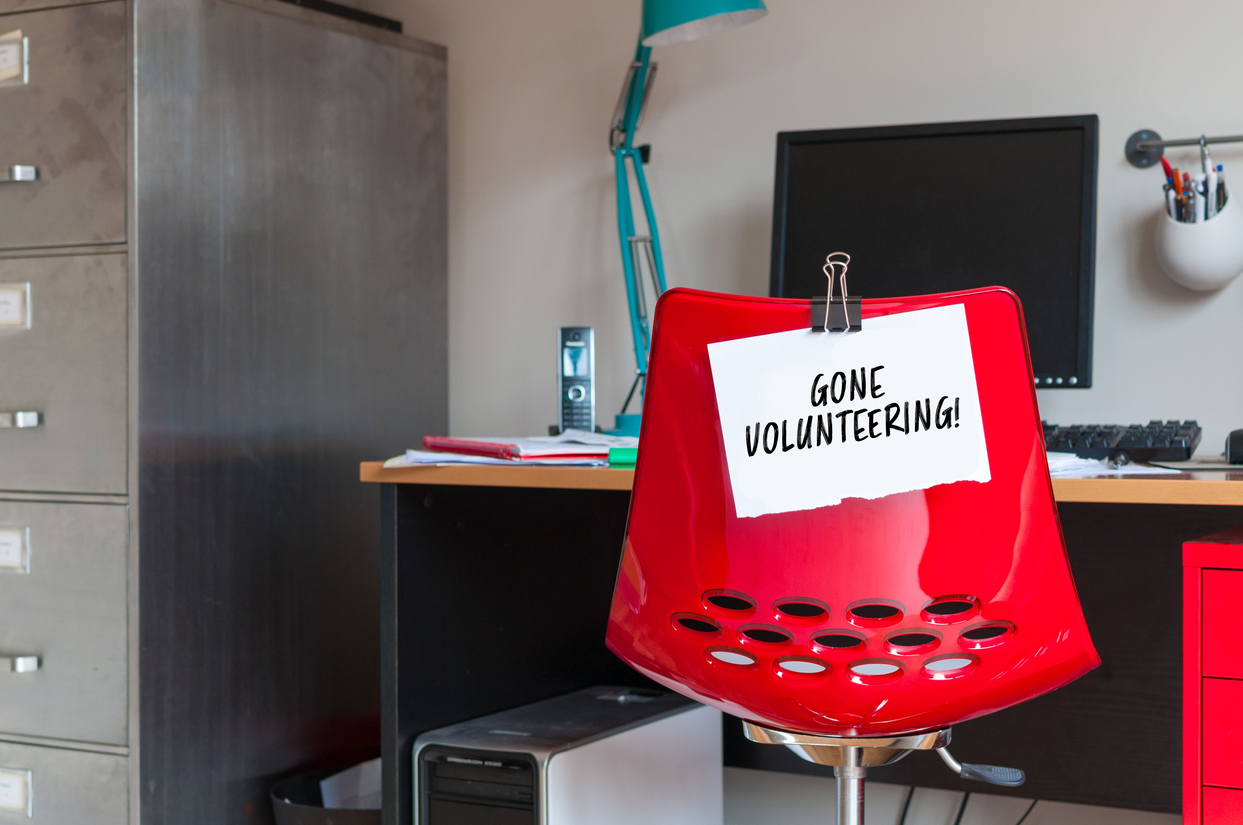 Office chair with a gone volunteering sign on it.