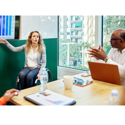 Woman in wheelchair presenting in a conference room.
