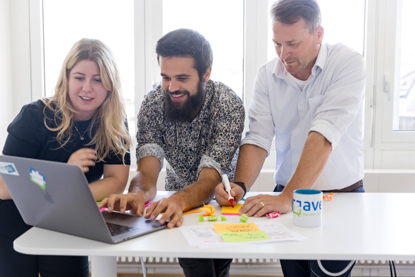 Workshop-Szene mit drei Mitarbeitenden, die an einer Lösung mit Post-its und Markern arbeiten
