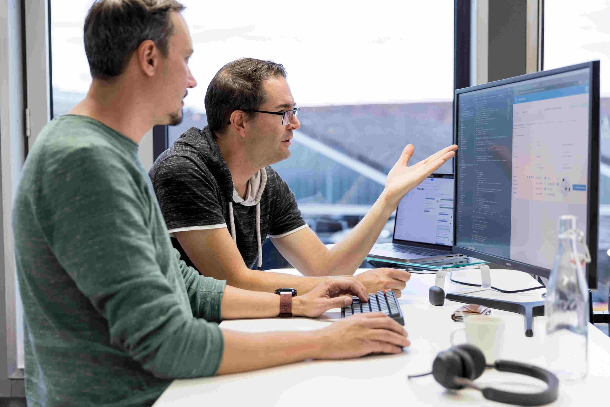 Zwei Software Entwickler diskutieren über Code an einem Bildschirm
