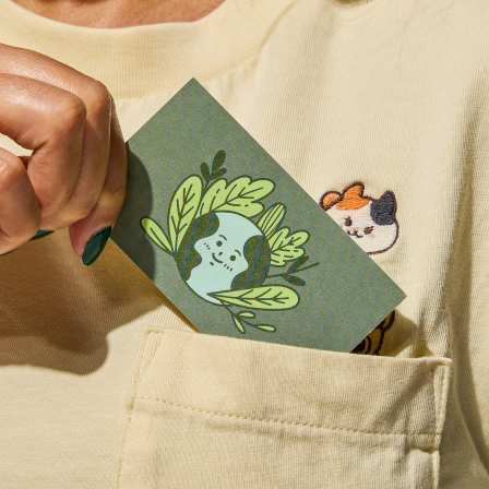 Hand holding an illustrated business card as it’s placed into a shirt pocket, highlighting the tactile and memorable nature of physical business cards.