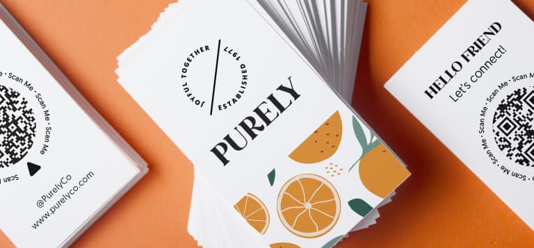 Stack of colorful business cards with orange illustrations and a QR code, showing a modern custom business card design for a small business.