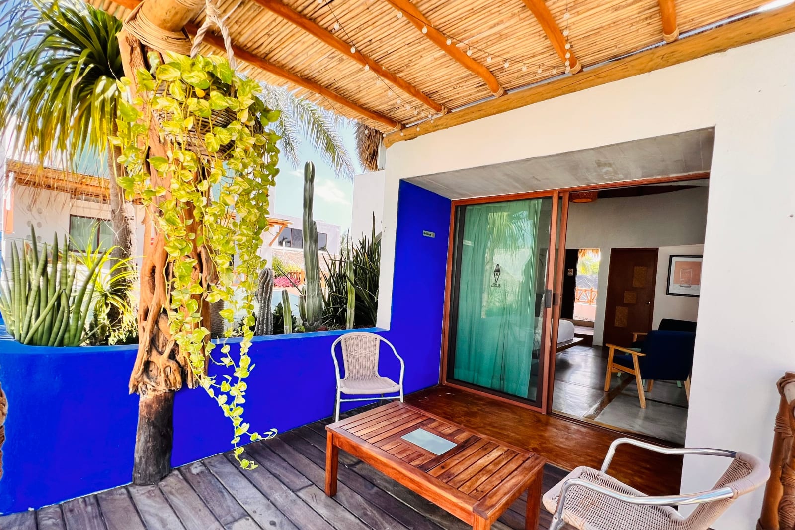 Terraza con muro azul, plantas colgantes y sillas