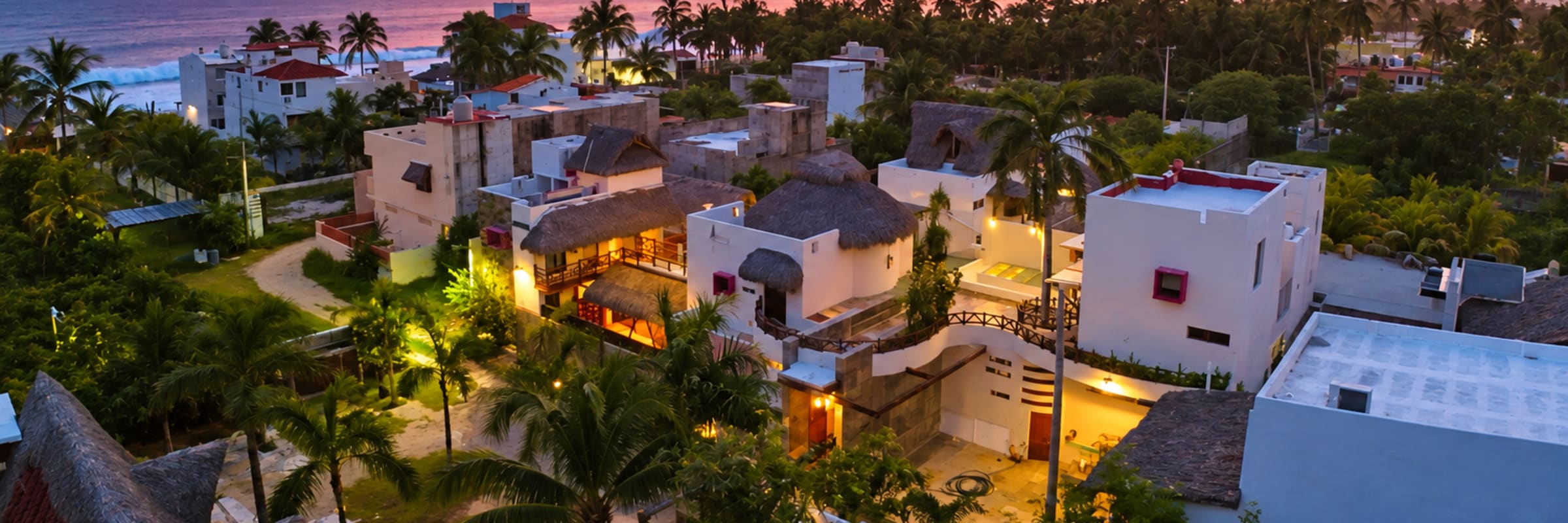 Vista aérea de A&V Hotel Boutique entre palmeras, con el mar al atardecer