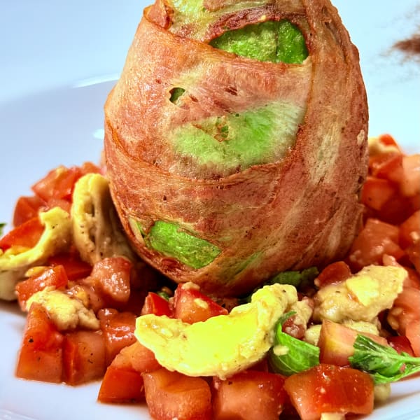 Aguacate envuelto en tocino sobre ensalada de jitomate