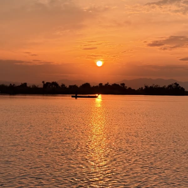 El sol sobre la Laguna de Coyuca, con una lancha a lo lejos
