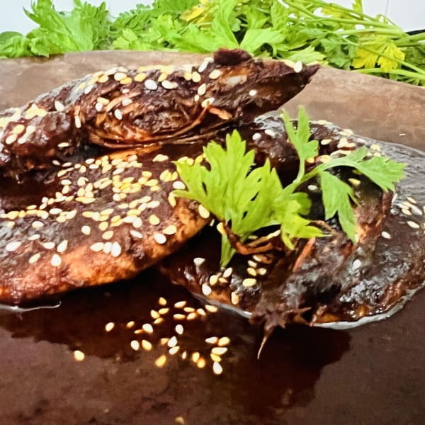 Camarones bañados en mole negro con ajonjolí y cilantro
