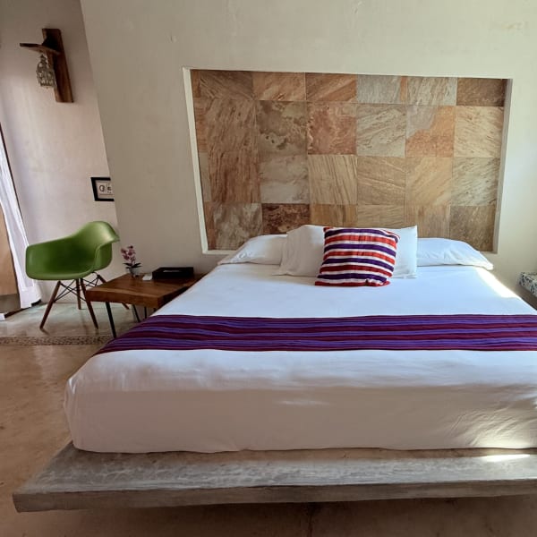 Habitación Pitaya con cama king, cabecera de piedra y banca de mosaico