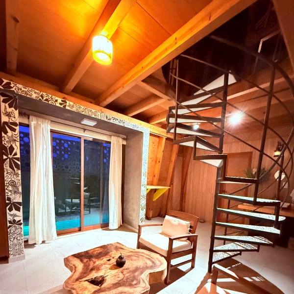 Sala de la habitación Tamarindo con escalera de caracol y ventanal a la alberca
