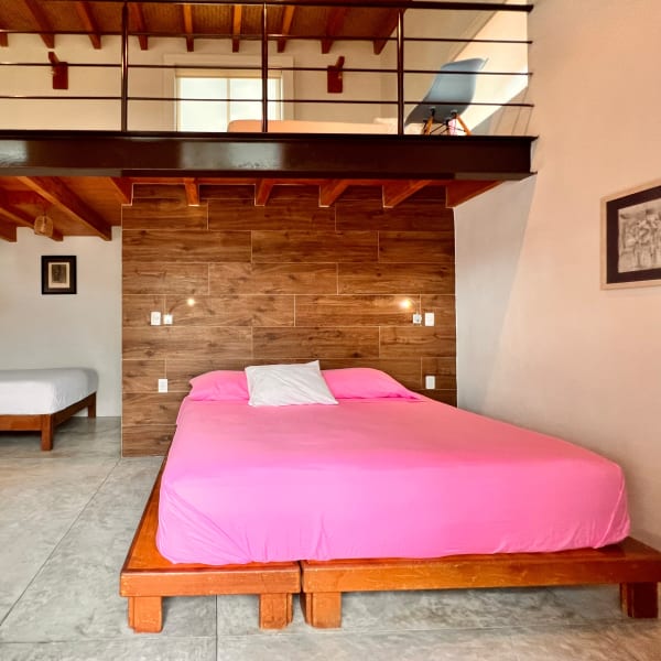 Habitación Tapanco con cama rosa bajo el tapanco de madera