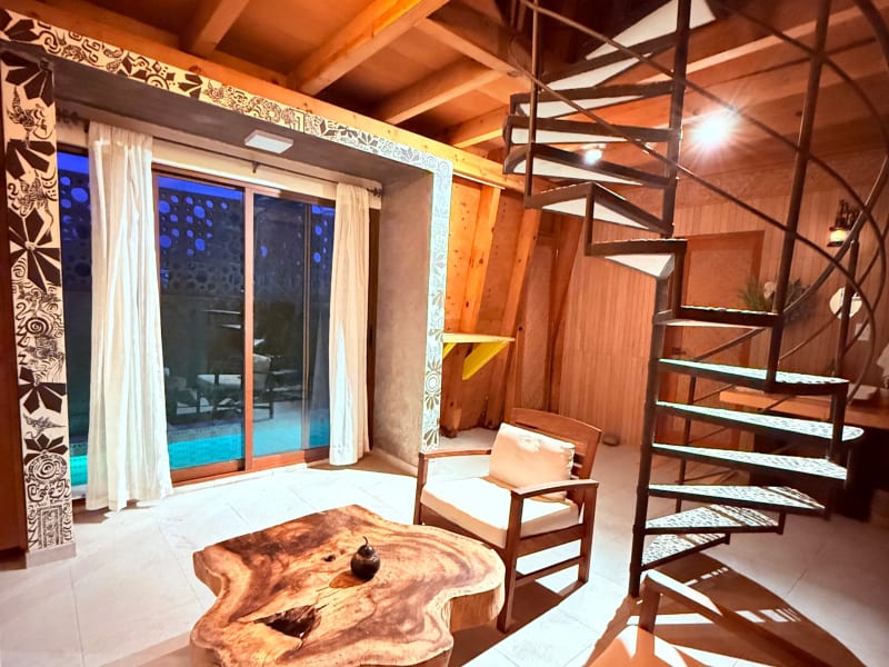 Sala de la habitación Tamarindo con escalera de caracol y ventanal a la alberca
