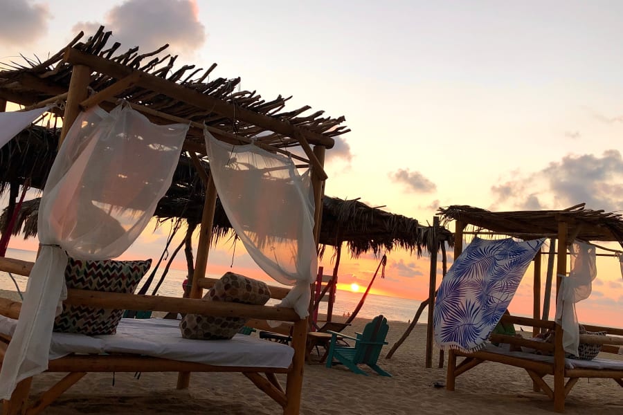 Camas con dosel en la playa al atardecer
