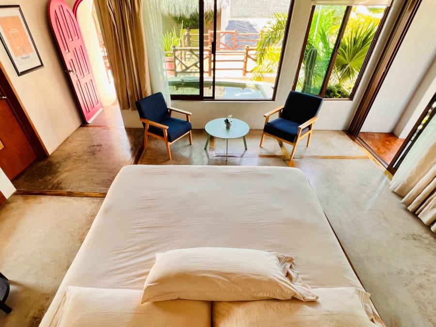 Cama frente a la sala con sillones azules
