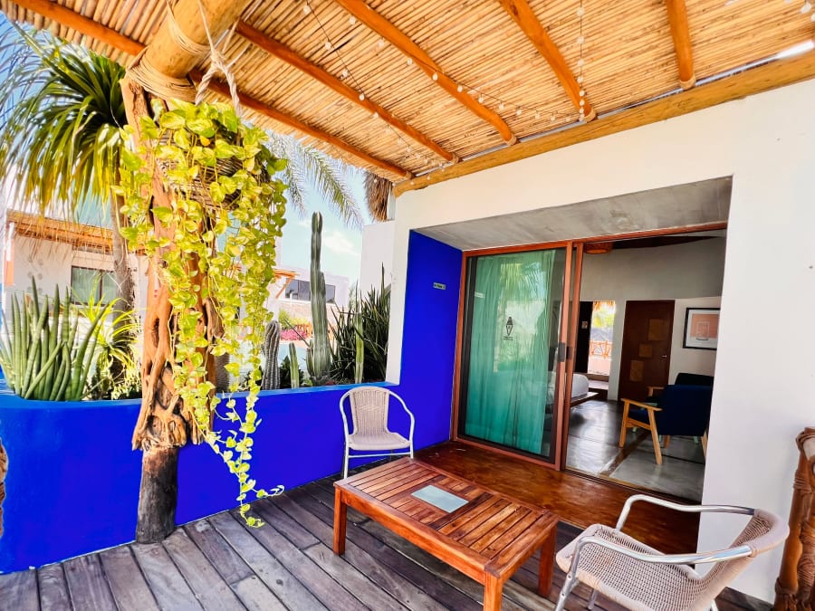 Terraza con muro azul, plantas colgantes y sillas