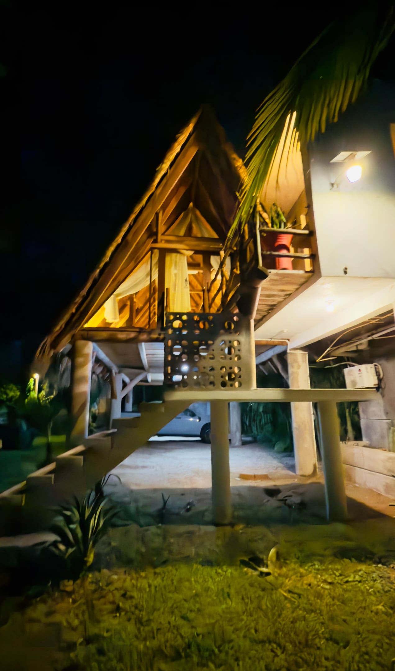 Cabaña de palapa sobre pilotes, iluminada de noche