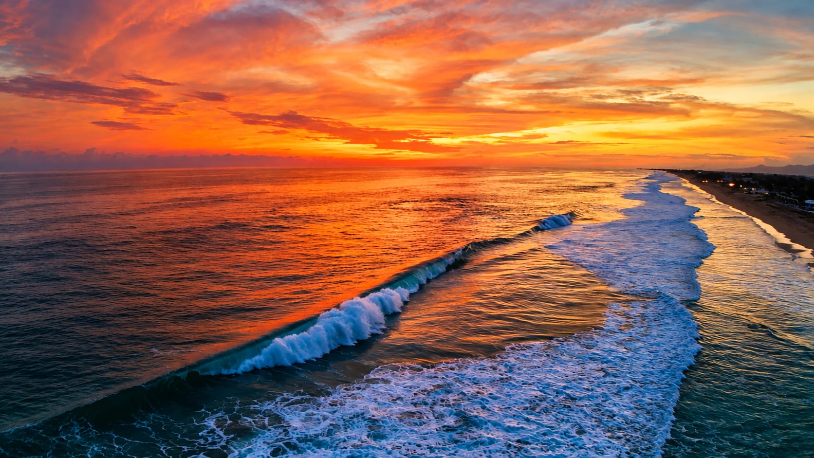 Vista aérea de las olas del Pacífico rompiendo frente a la playa al atardecer