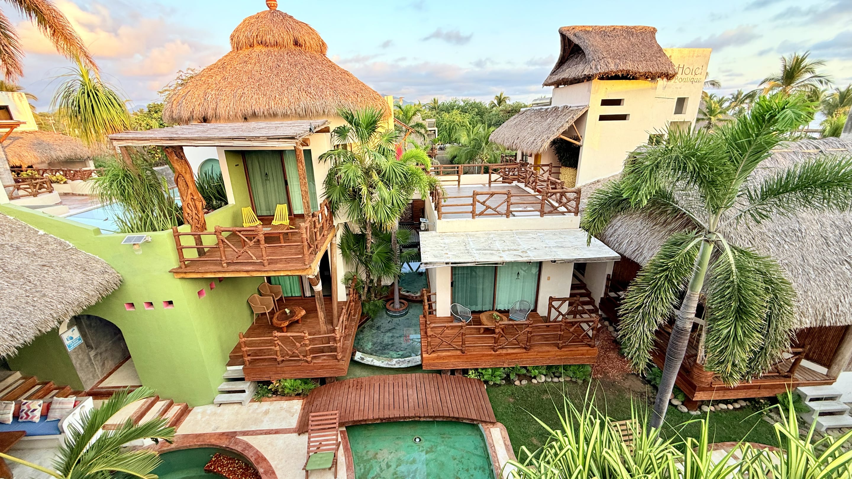 Habitaciones con terrazas de madera y techos de palapa sobre la alberca