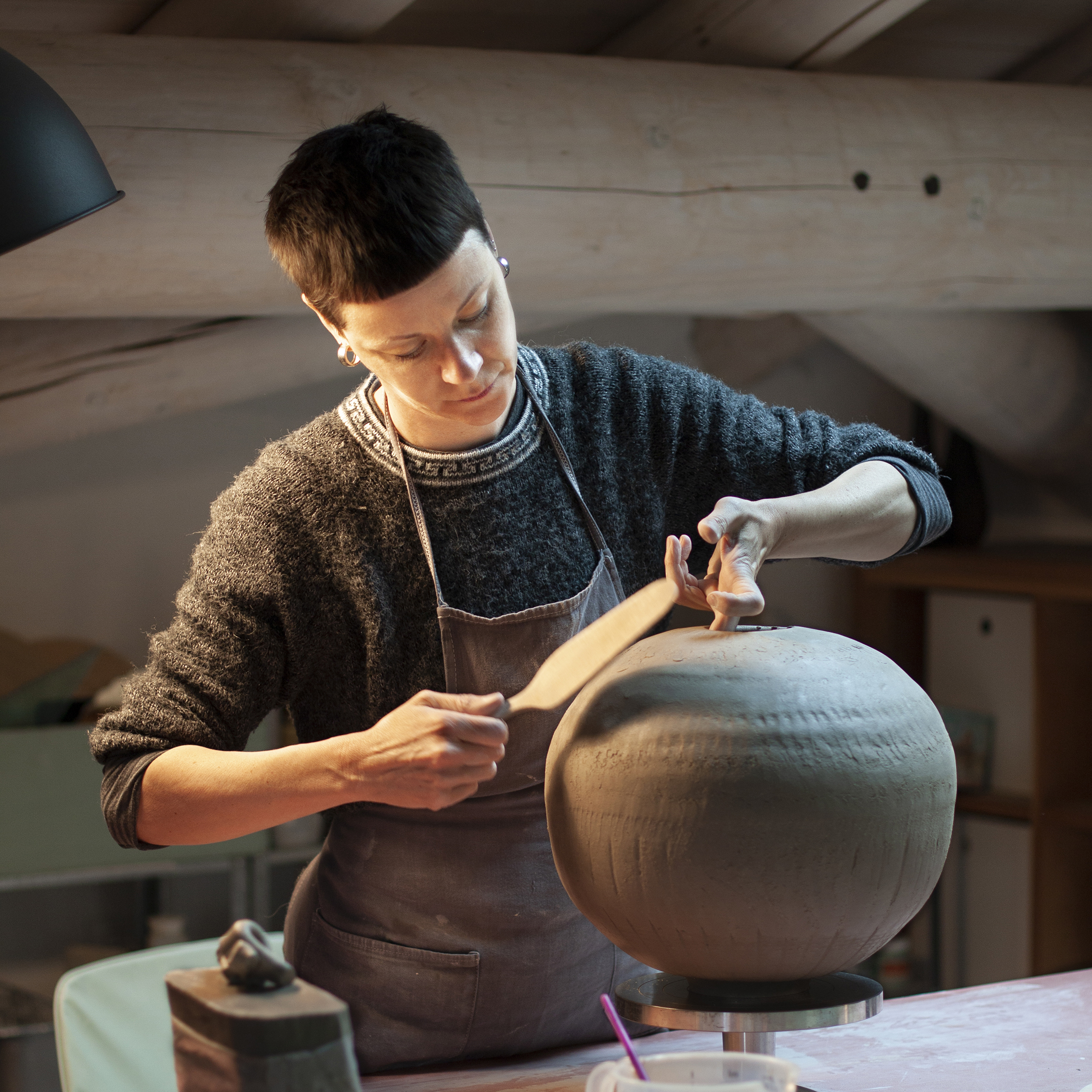 Elena Milani shaping a large stoneware vase in her studio
