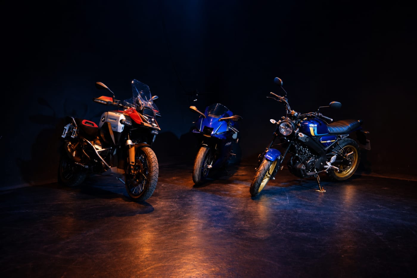 Tres motos en penumbra en el centro de un escenario oscuro
