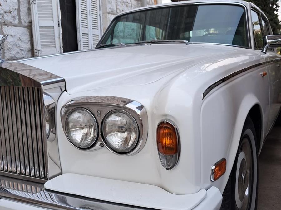 Close-up of the white Rolls-Royce Silver Shadow's round headlights and chrome grille
