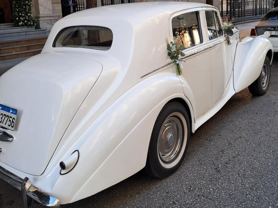 Rear three-quarter view of the white 1953 Bentley R Type with flowers on the doors