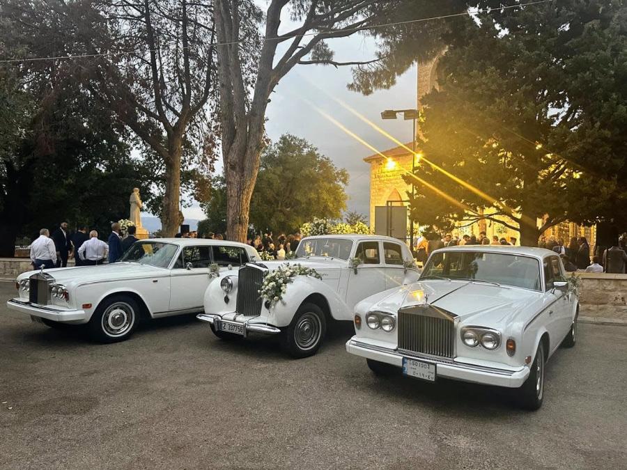 White 1953 Bentley R Type with flowers between two white Rolls-Royce Silver Shadows at sunset