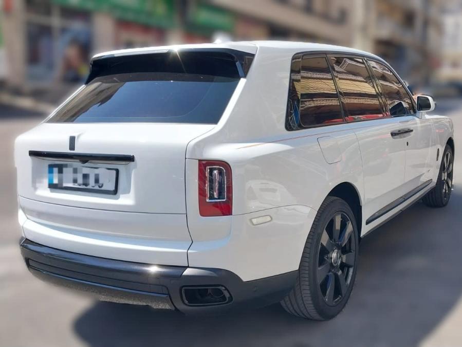 Rear three-quarter view of a white 2022 Rolls-Royce Cullinan with black wheels and tinted windows