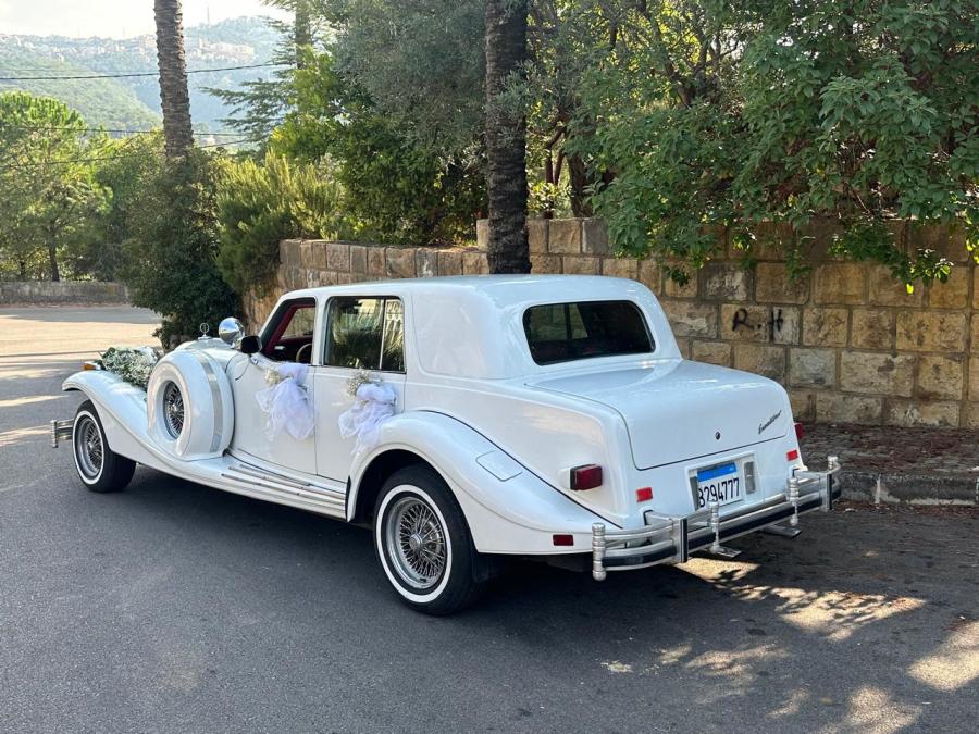 Rear three-quarter view of the white 1978 Excalibur sedan with ribbons