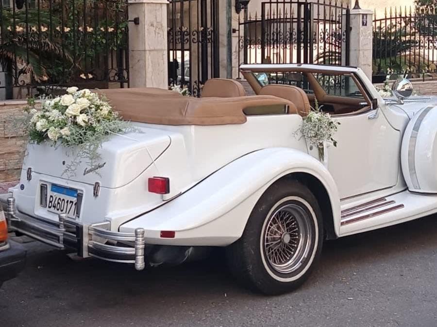 Rear view of the white 1978 Excalibur convertible with flowers on the trunk