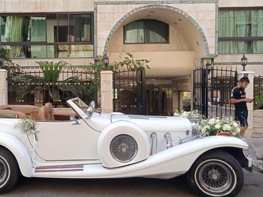 Side view of the white 1978 Excalibur convertible with flower decorations