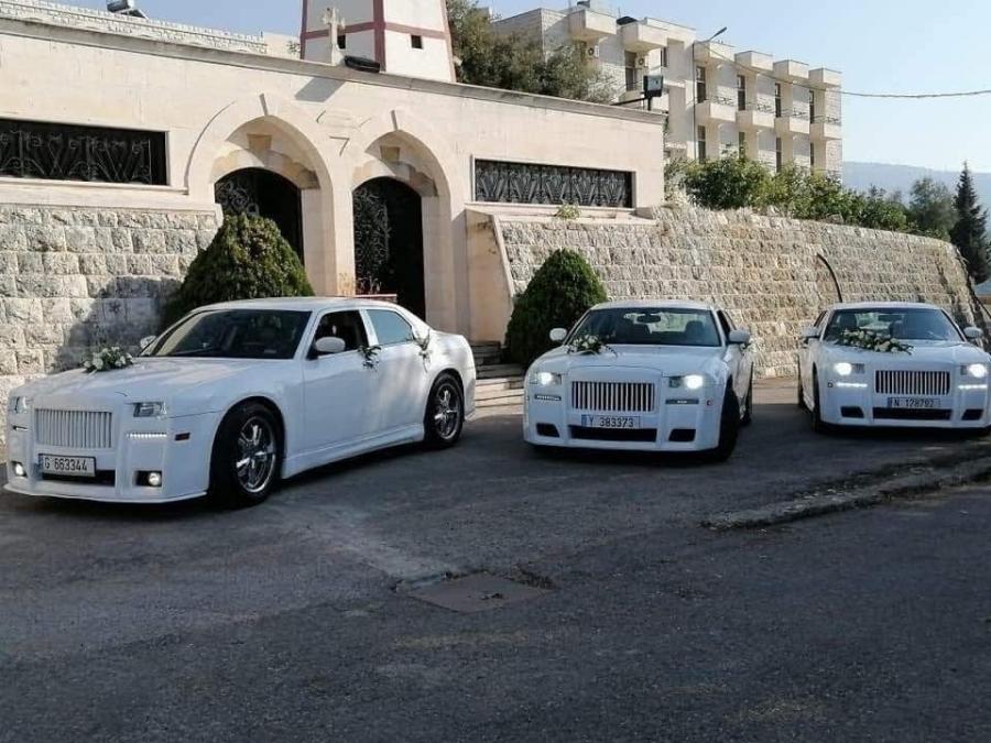 Three matching white Chrysler 300C Phantom-look sedans outside a stone building