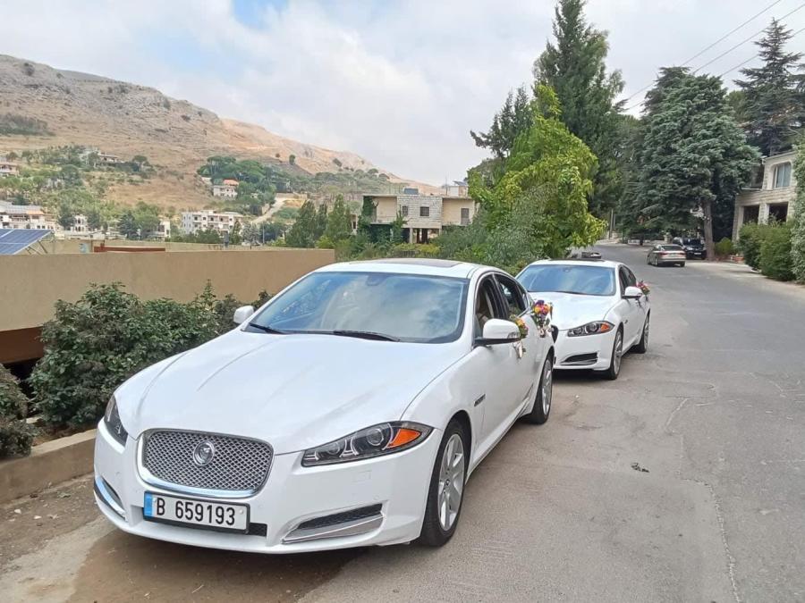 Two white Jaguar XF sedans on a mountain road