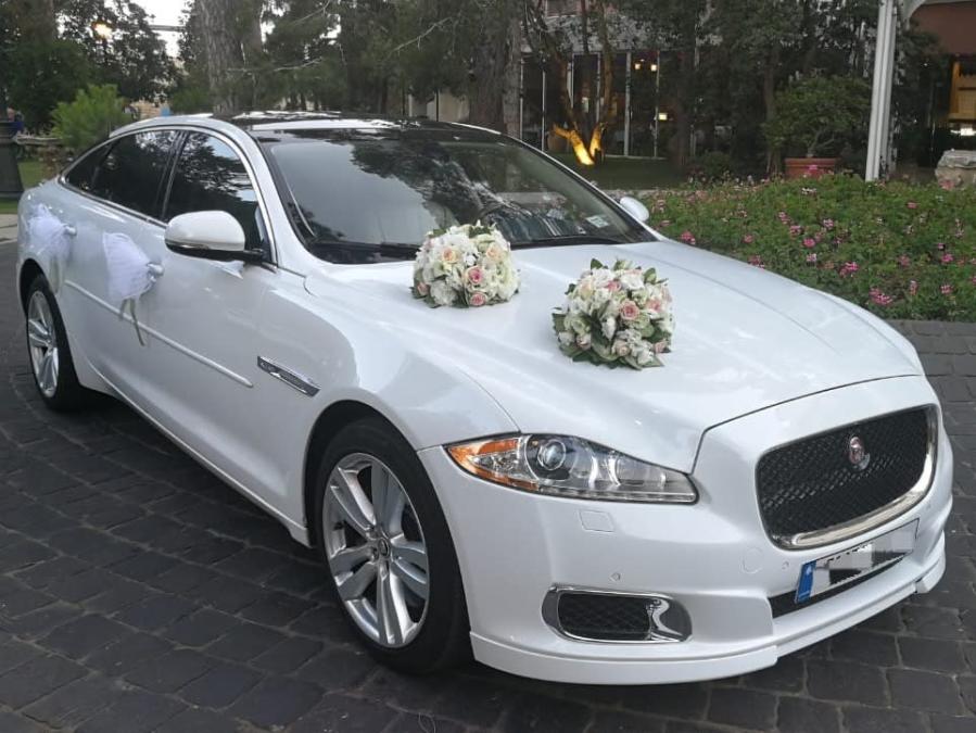 White Jaguar XJL with two white flower bouquets and ribbons, front view