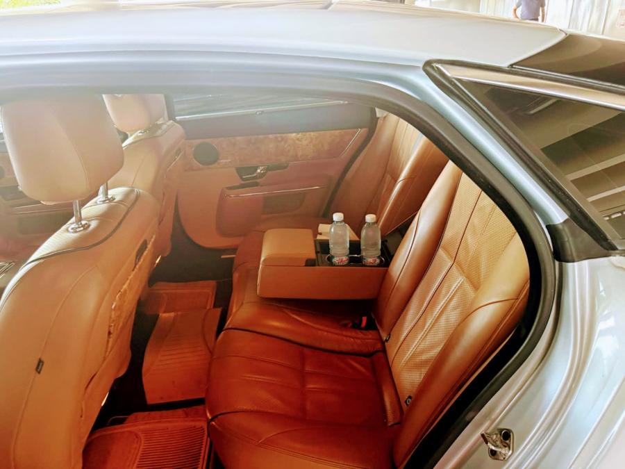 Tan leather rear seats of the Jaguar XJL with bottled water in the center console