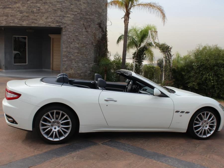 White Maserati GranCabrio with the top down, side view by palm trees