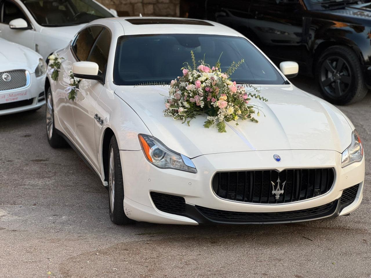 White Maserati Quattroporte with a pink and white flower bouquet on the hood