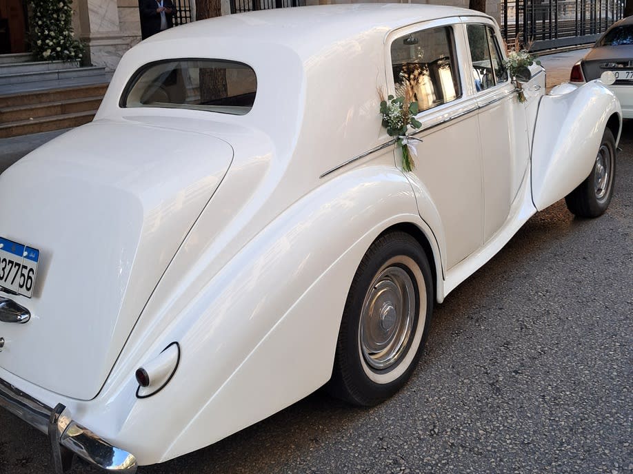 Rear three-quarter view of the white 1953 Bentley R Type with flowers on the doors