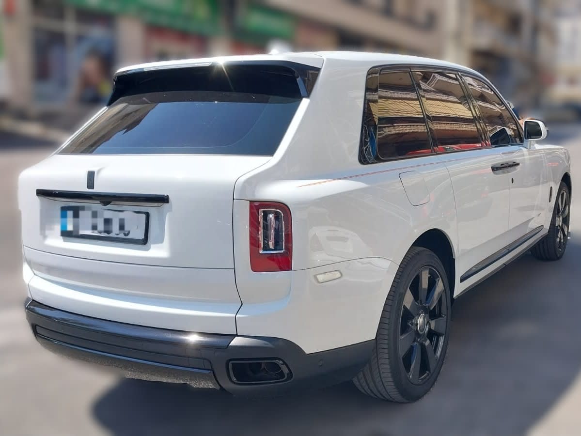 Rear three-quarter view of a white 2022 Rolls-Royce Cullinan with black wheels and tinted windows