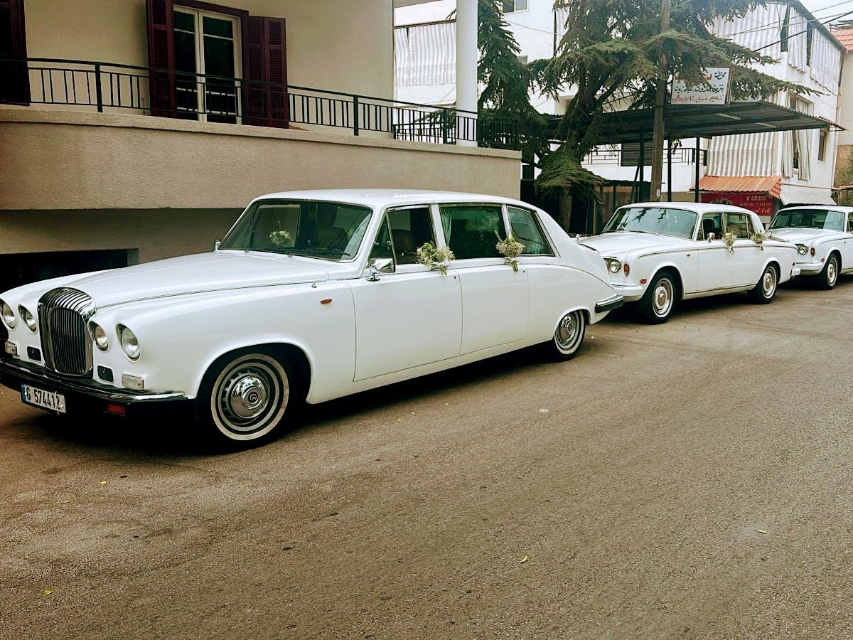 Three white Daimler DS420 limousines lined up on a street