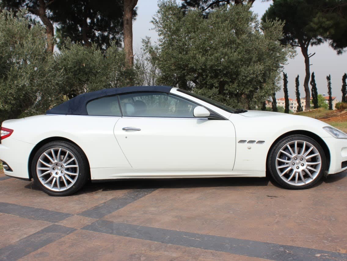 White Maserati GranCabrio with its dark blue soft top up, side view
