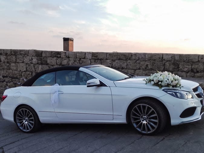 White Mercedes E-Class convertible with a black soft top and white roses, in Byblos