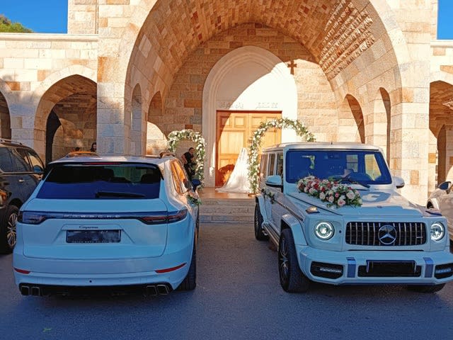 Decorated white G-Class at St. Stephen Church, Batroun, next to a white Porsche Cayenne