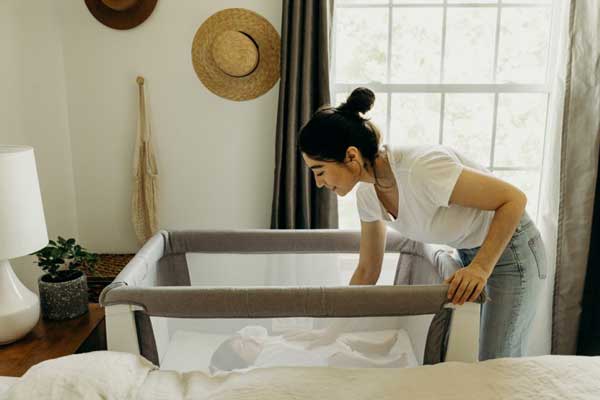 parent putting baby in bedside sleeper