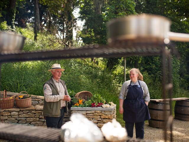 Our head of productive growing, David and chef, Beth at the outdoor fire pit with their seasonal produce